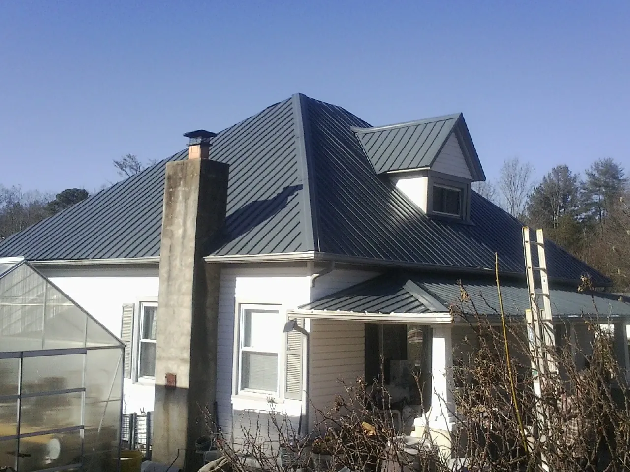 Dark blue standing seam metal roof on a white farmhouse with dormer — Slate & Tile Roof Repair by Roofing Brothers in College Place