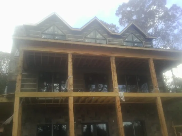 Dormers and porch framing on a large log home under construction — Roof Coating work by our crew in College Place