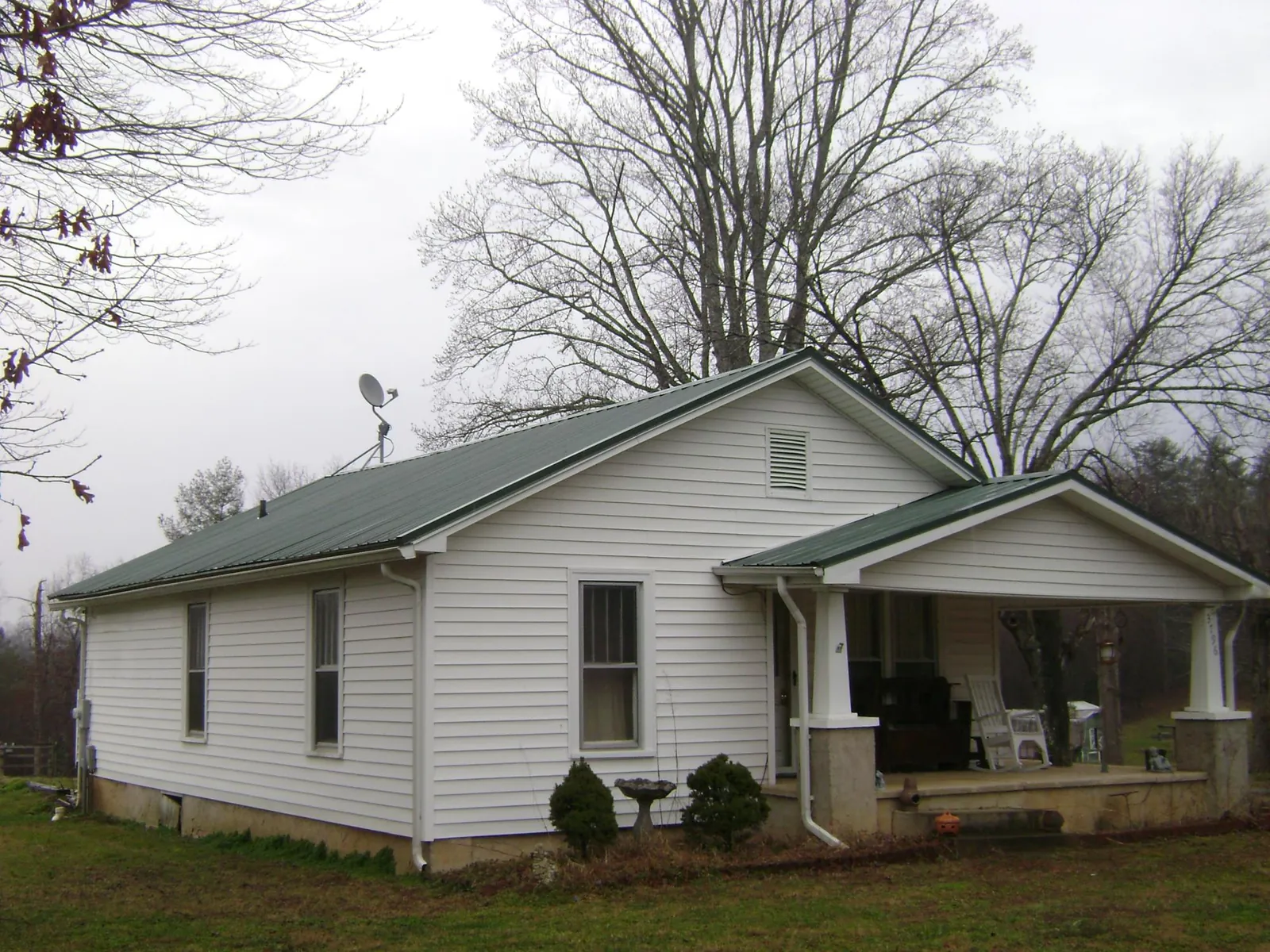 Green metal roof on a white bungalow with a side porch in College Place