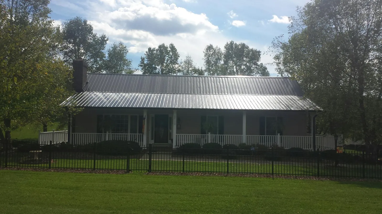 Gray metal roof on a brick ranch with a full width front porch — Gutter Guard Installation work by our crew in College Place