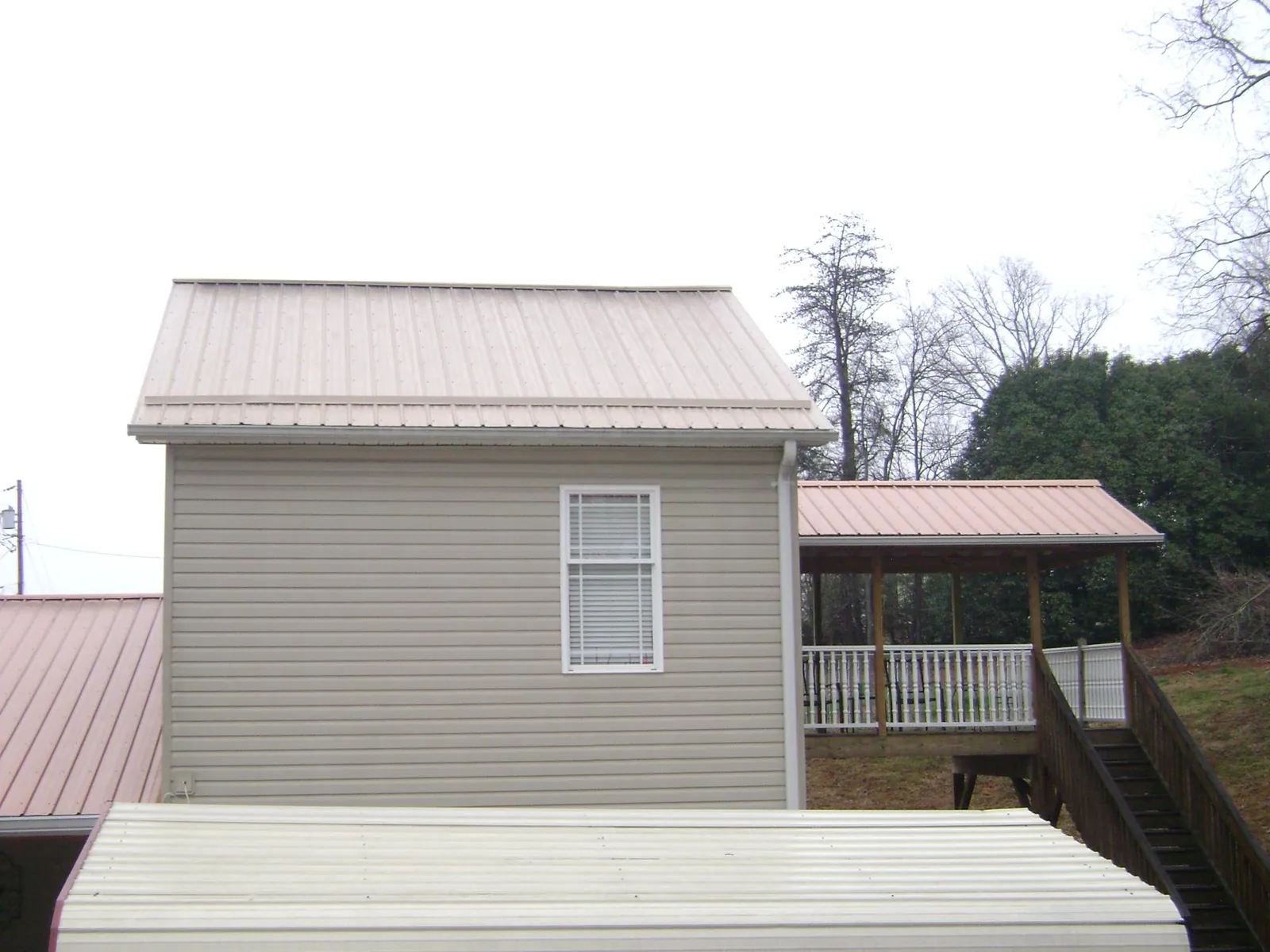 Tan metal roofs on a two story addition and attached porch, from a Roof Replacement job in College Place