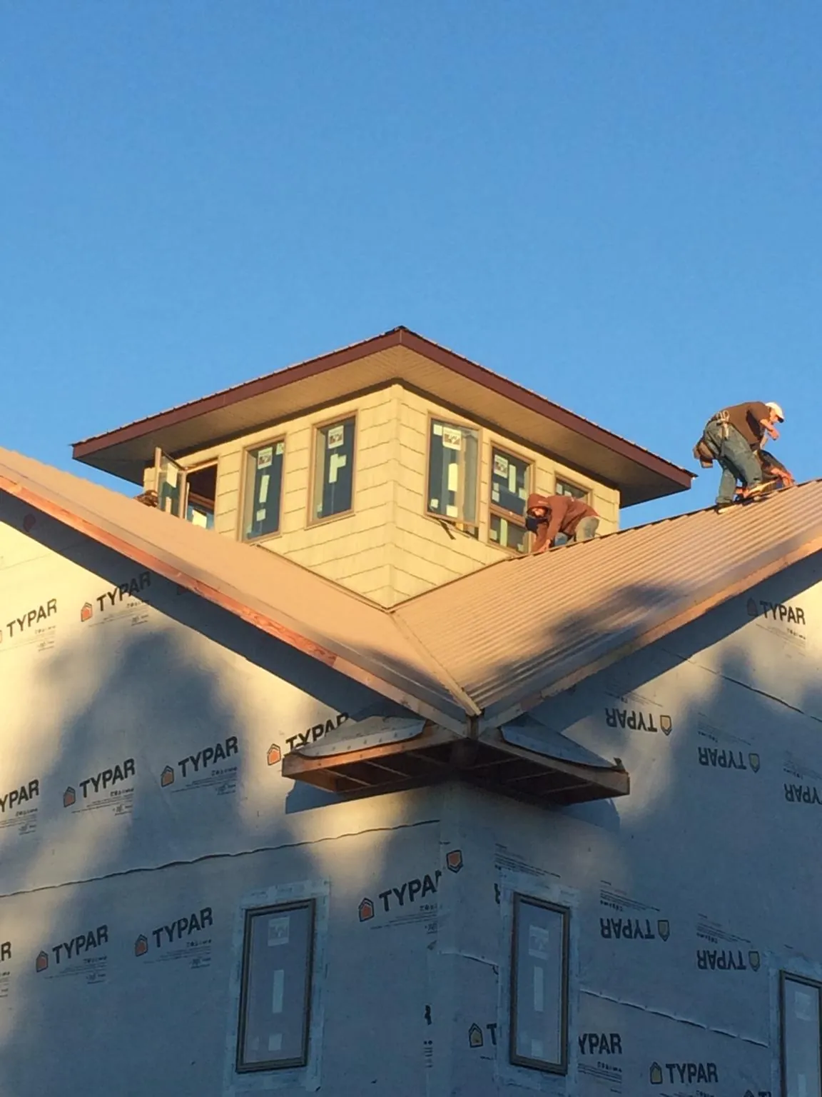 Roofers working around a rooftop cupola on a new metal roof at sunset — Roof Waterproofing in College Place by Roofing Brothers